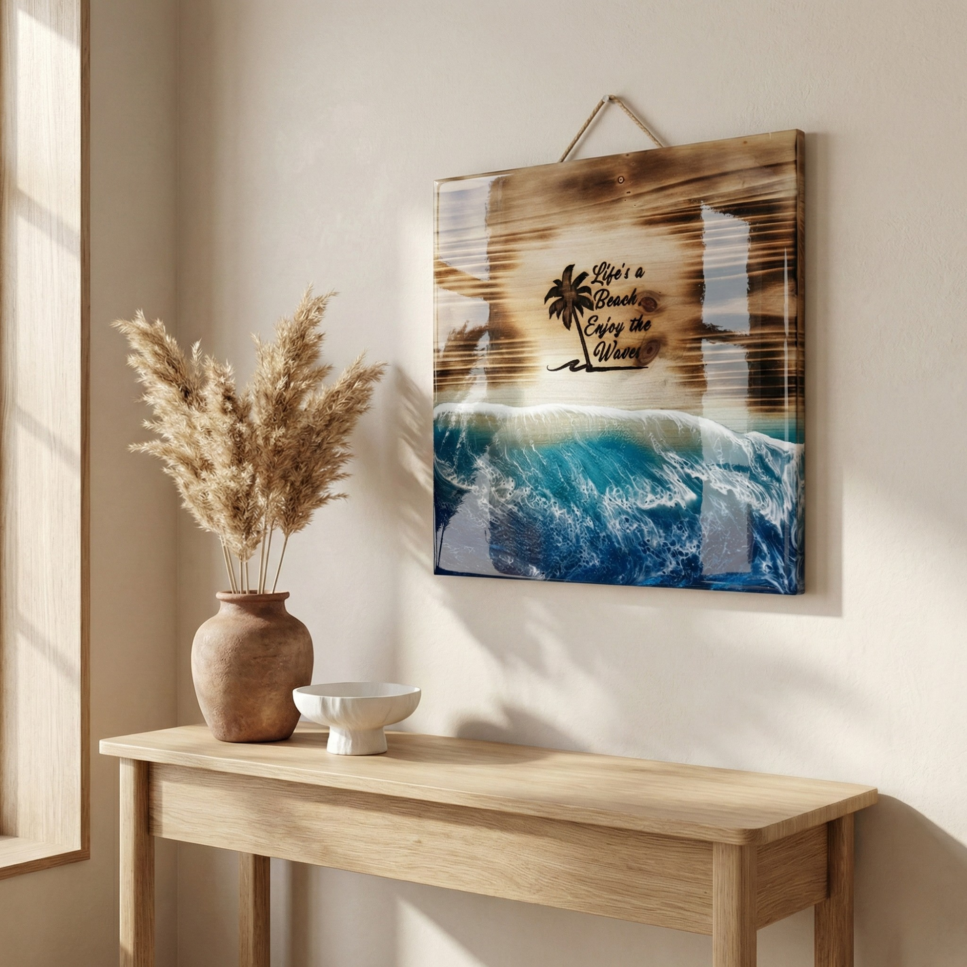 Decorative wall art with beach theme on a wall above a wooden console table with a vase and bowl.
